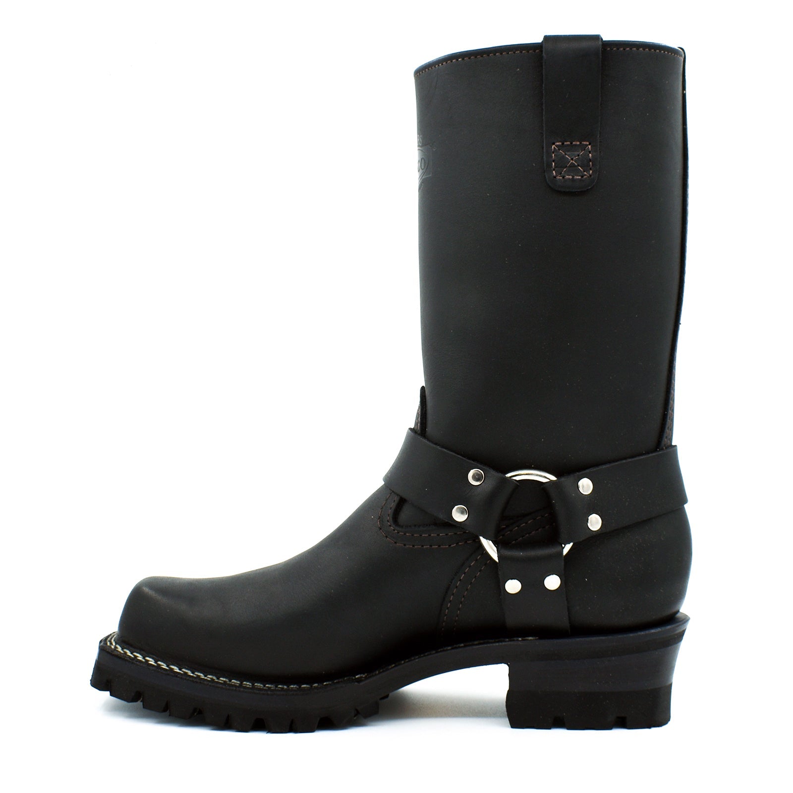 Close-up of chrome D-ring and polished nickel rivet harness strap system wrapping ankle of black oiled leather engineer boot