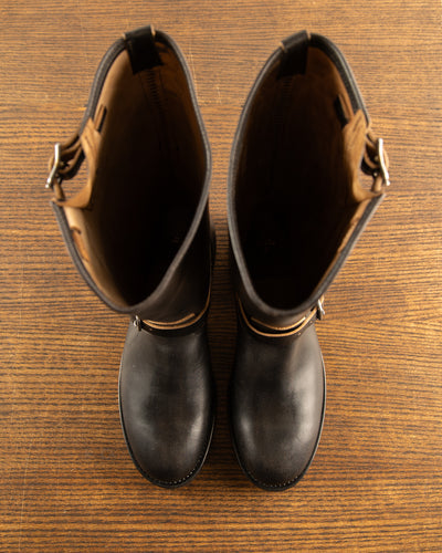 Upper collar detail of black tall engineer boots showing subtle side buckle tab for personalized shaft fit and secure collar closure