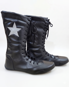 Side profile of black smooth leather knee-high wrestling boots displaying white star patch detail and wide structured padded collar