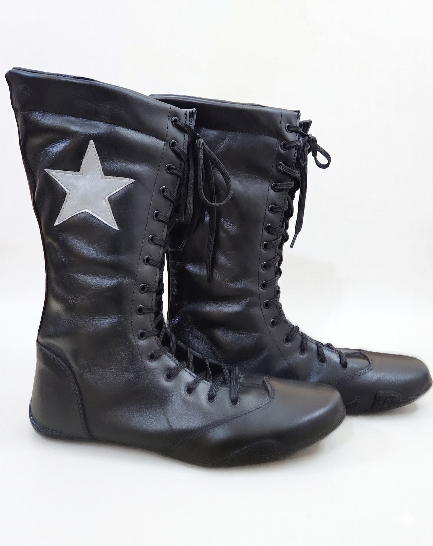 Side profile of black smooth leather knee-high wrestling boots displaying white star patch detail and wide structured padded collar