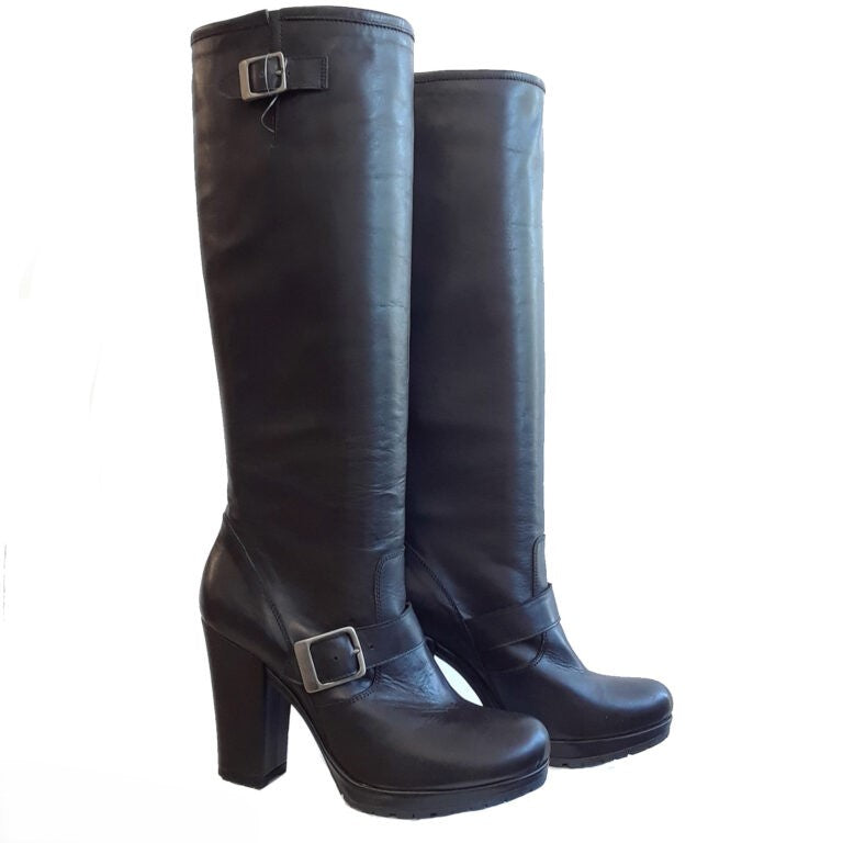 Black leather women's knee-high engineer boots with dual gunmetal silver buckle straps, chunky block heel, and side zipper on white background