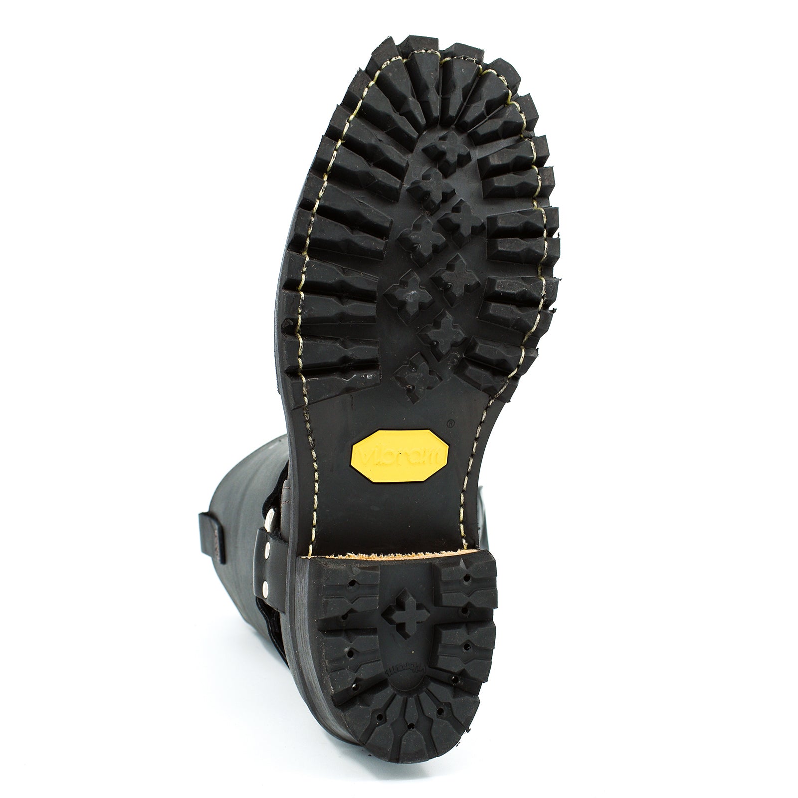 Close-up of a black boot sole with a yellow label on a white background
